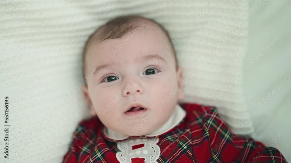 Adorable caucasian baby lying on bed with relaxed expression at bedroom Adorable caucasian baby lying on bed with relaxed expression at bedroom