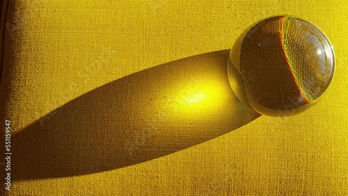 Bola de cristal con reflejo del sol sobre fondo amarillo
