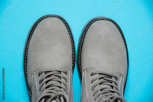 Gray women's winter boots with laces on a blue background. Concept of modern female fashion