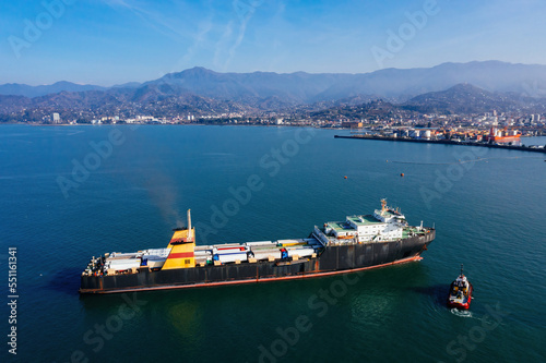 Cargo ship with containers and trucks, aerial drone view