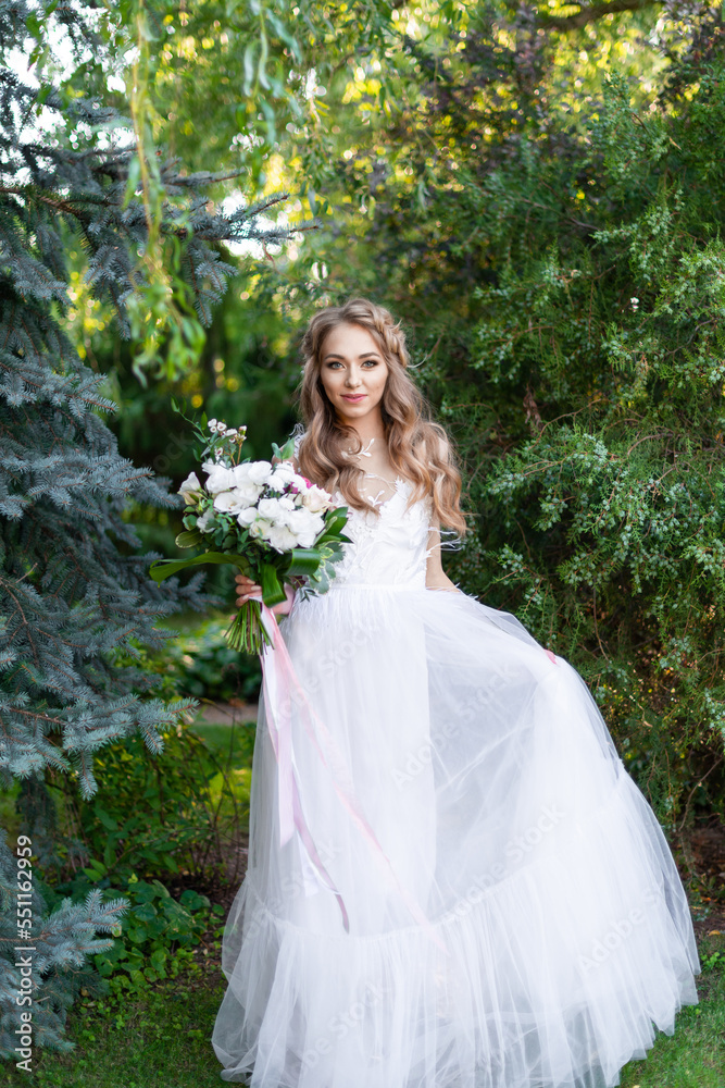 bride in a white wedding dress holds a beautiful wedding bouquet in her hand in the garden