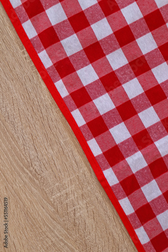 Checkered picnic cloth on wooden table, top view. Space for text