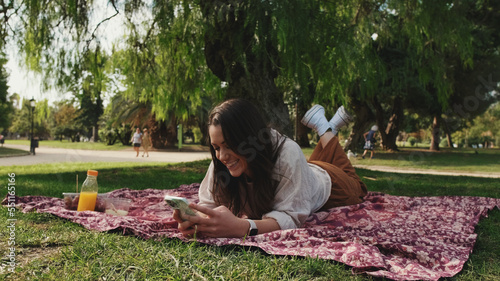 Young woman is resting in the park and using mobile phone © Andrii Nekrasov