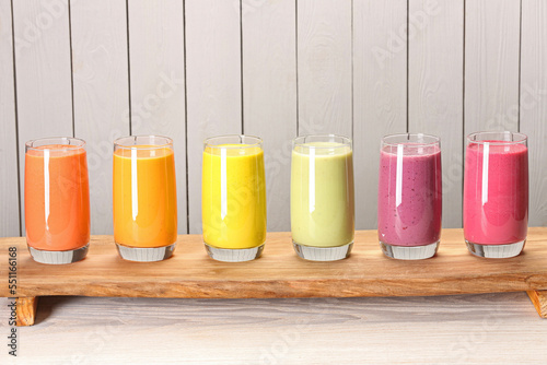 Board with many different tasty smoothies against white wooden background, space for text