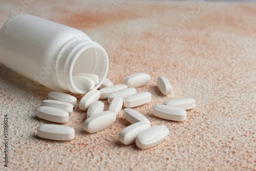 White medical bottle and pills on color textured surface, closeup. Space for text