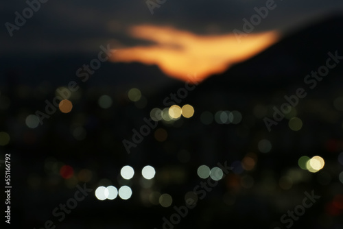 Blurred view of beautiful sunset with mountains in city, bokeh effect