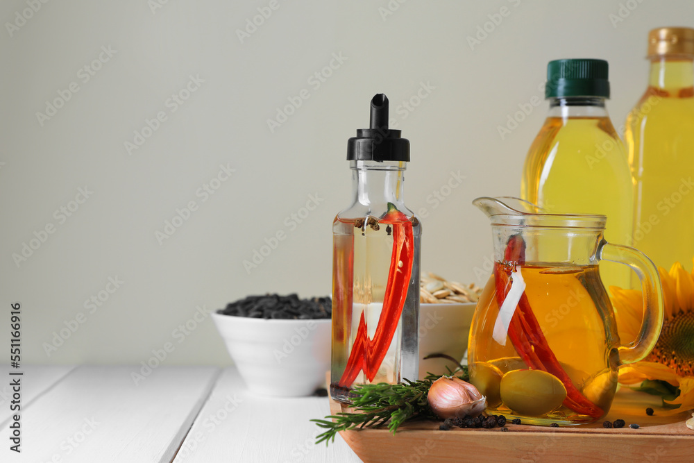 Different cooking oils and ingredients on white wooden table against light background, space for text Different cooking oils and ingredients on white wooden table against light background, space for text