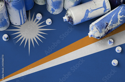 Marshall Islands flag and few used aerosol spray cans for graffiti painting. Street art culture concept, vandalism problems photo