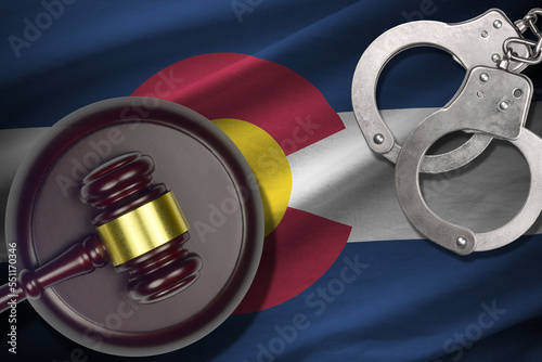 Colorado US state flag with judge mallet and handcuffs in dark room. Concept of criminal and punishment, background for guilty topics photo