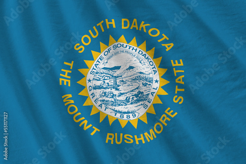 South Dakota US state flag with big folds waving close up under the studio light indoors. The official symbols and colors in fabric banner photo