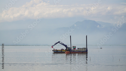 dredger equipped with excavator on the lake to clean from garbage