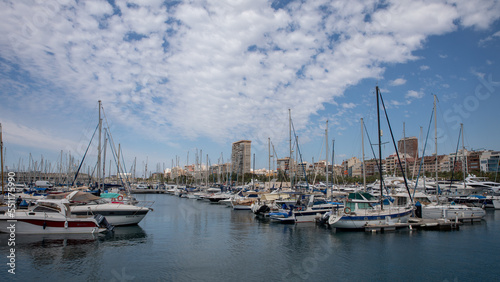 Beautiful port of Alicante, Spain at Mediterranean sea. Luxury yachts, ships, ferries and fishing boats sailing and standing in rows in harbor