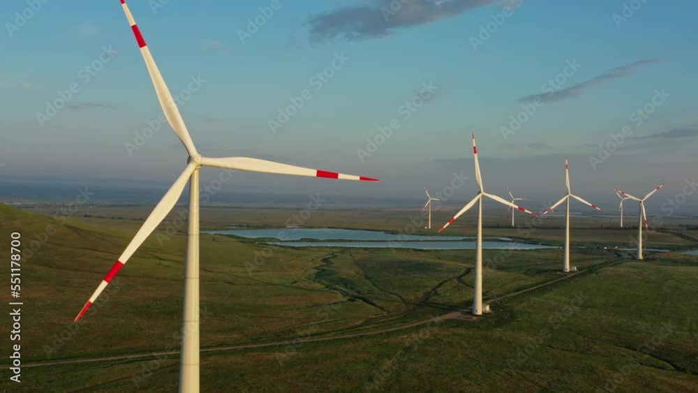 Beautiful aerial sunset landscape with lake and windmills or wind turbine on wind farm in rotation to generate electricity energy, 4k Beautiful aerial sunset landscape with lake and windmills or wind turbine on wind farm in rotation to generate electricity energy, 4k