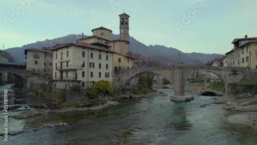 Aerial villagescape - old church and crossing rivers with mountains backdrop, San Giovanni Bianco Village, Valbrembana, Bergamo, Lombardy, Italy