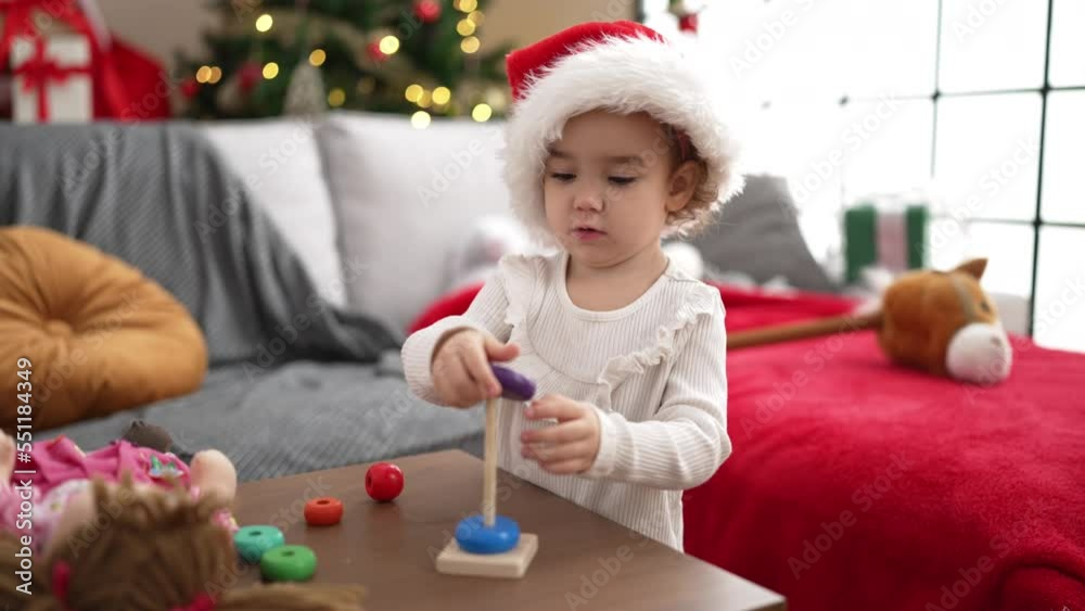 Adorable caucasian girl playing with toy standing by christmas tree at home Adorable caucasian girl playing with toy standing by christmas tree at home