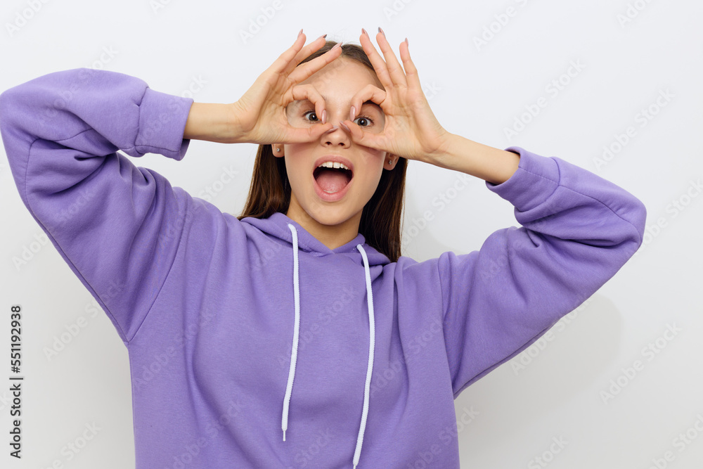 an admiring woman stands on a white background in a purple suit happily looks forward having made glasses out of her fingers and leaned them against her eyes smiling happily an admiring woman stands on a white background in a purple suit happily looks forward having made glasses out of her fingers and leaned them against her eyes smiling happily