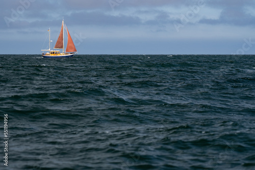 Lonely Sailing boat on blue open sea. Concept of loneliness, solitude and desolation