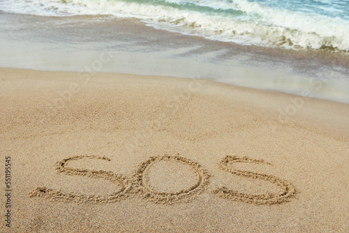 Message SOS drawn on sand near sea