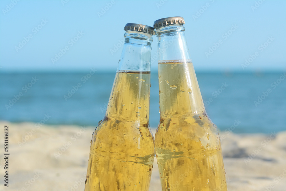 Bottles of cold beer on beach near sea, closeup Bottles of cold beer on beach near sea, closeup