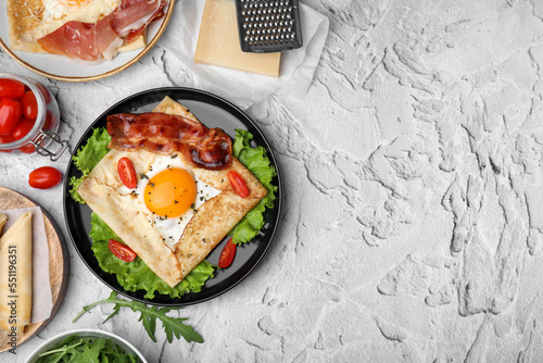 Fotografie Delicious crepe with egg served on light gray textured table, flat lay with space for text