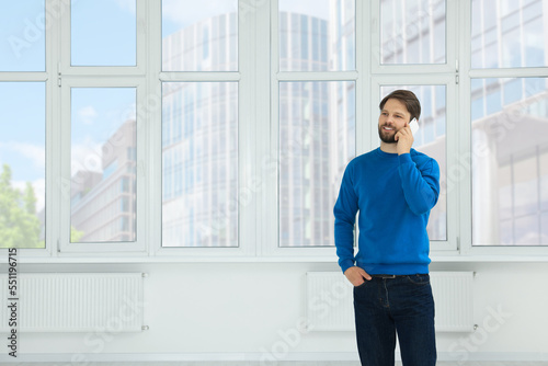 Man in casual clothes talking on phone indoors, space for text