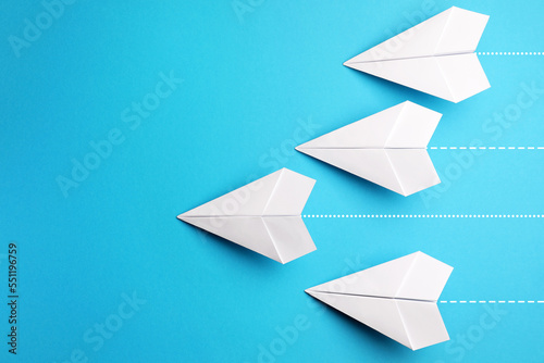 Handmade white paper planes on light blue background, flat lay. Space for text