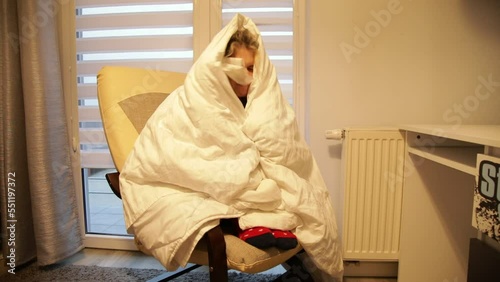 Sick woman in room with dim light wrap up in warm white blanket. Sneeze, blow nose into handkerchief and throw out.