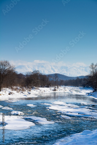 冬の河原と雪山と青空 十勝岳連峰 