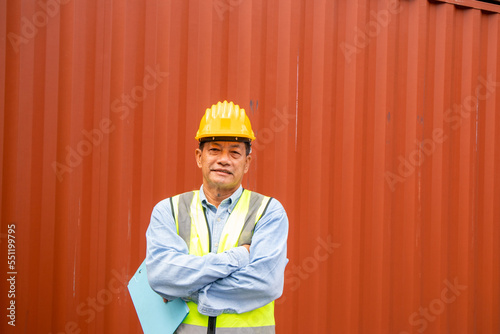 Portrait of confident senior asian engineer holds documents with container background.