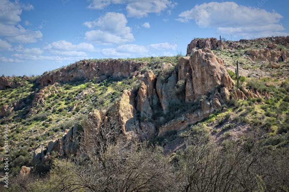Ancient rocks and hills at the Boyce Thompson Arboretum, Arizona. There is a cloud in the blue sky.