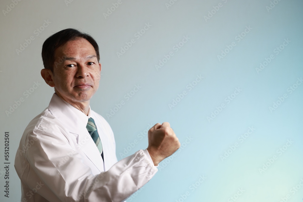 Middle-aged Asian doctor in a white coat on blue background. Concept image of regenerative medicine, vaccine development and advanced therapy. Middle-aged Asian doctor in a white coat on blue background. Concept image of regenerative medicine, vaccine development and advanced therapy.