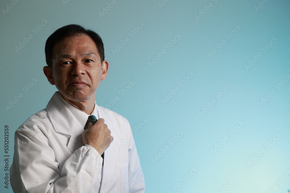 Middle-aged Asian doctor in a white coat on blue background. Concept image of regenerative medicine, vaccine development and advanced therapy. Middle-aged Asian doctor in a white coat on blue background. Concept image of regenerative medicine, vaccine development and advanced therapy.