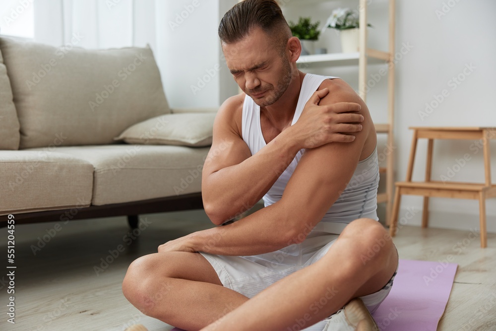 Man sports injury during workout at home arm and leg pain, pumped up man fitness trainer works out at home, the concept of health and body beauty Man sports injury during workout at home arm and leg pain, pumped up man fitness trainer works out at home, the concept of health and body beauty