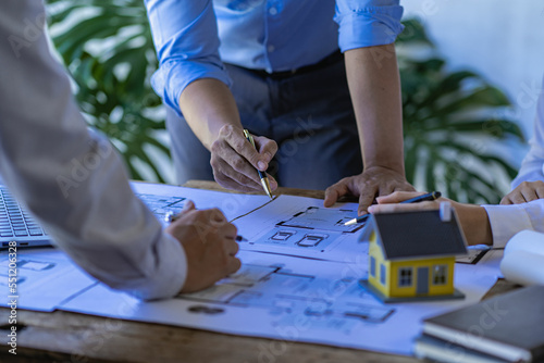  Engineering team meeting for colleagues discussing and reviewing blueprints at desk in office Engineers and workers planning for construction and renovation building projects in workplace