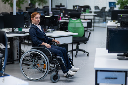 Caucasian woman wheelchair in open space office.