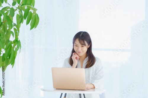 頬杖をついてパソコンを見つめる若い女性