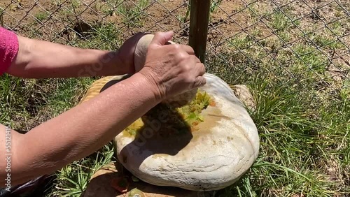 cámara lenta de mujer peruana moliendo de manera tradicional rocoto en piedras (batán y chungo)