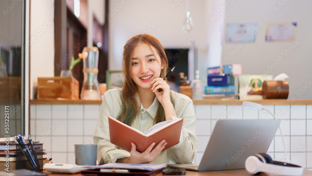 Remote work concept, Woman entrepreneur reading a book and smiling while working in coworking space Remote work concept, Woman entrepreneur reading a book and smiling while working in coworking space