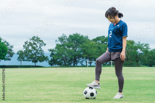 サッカー場でユニフォームを着てサッカー・フットサルの練習をする日本人女性  © buritora
