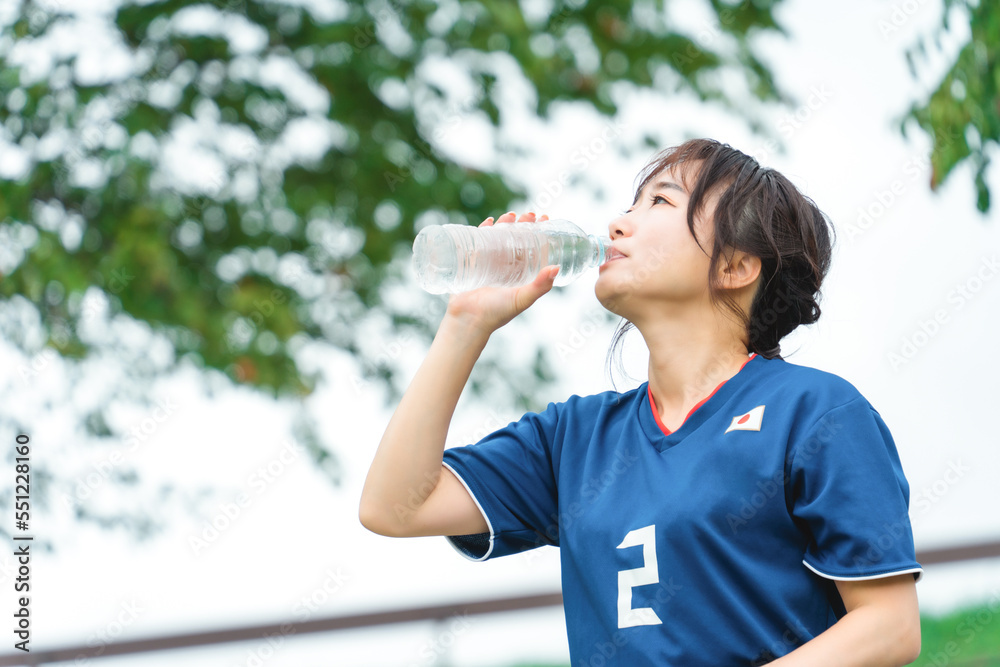サッカー観戦しながら熱中症対策・暑さ対策のため水を飲むサッカーファン・サポーターのアジア人女性
サッカー観戦しながら熱中症対策・暑さ対策のため水を飲むサッカーファン・サポーターのアジア人女性