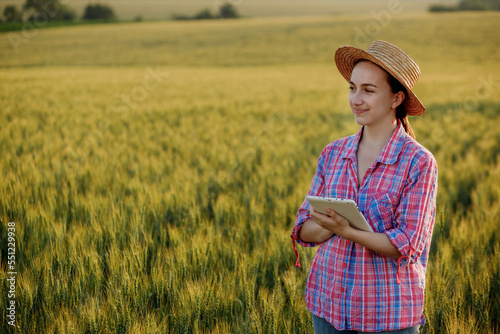 A young fcrmer checks a grain field and sends data to the cloud from a tablet. Concept of smart farming and digital agriculture. Successful production and cultivation of organic food products