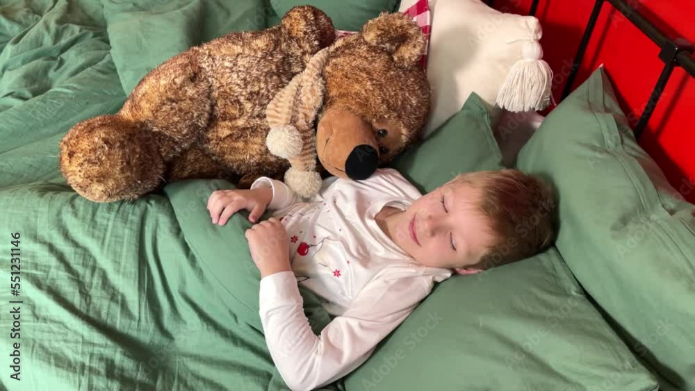 The child sleeps before Christmas. A little boy in Christmas pajamas lies in a green bed. Christmas morning. New Year and holidays The child sleeps before Christmas. A little boy in Christmas pajamas lies in a green bed. Christmas morning. New Year and holidays