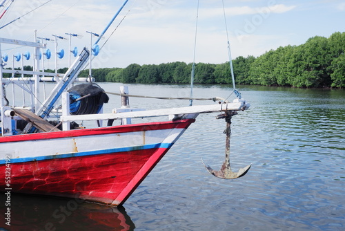 the front side of a large fishing boat moored in the harbor. anchor hanging, seen from below