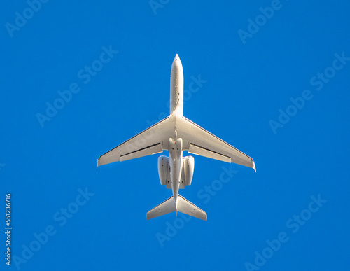 White private jet against blue sky traveling north