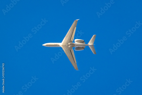 White private jet against blue sky traveling  west