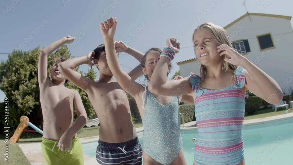 Children dancing at poolside raising hands, having fun together. Boys ...