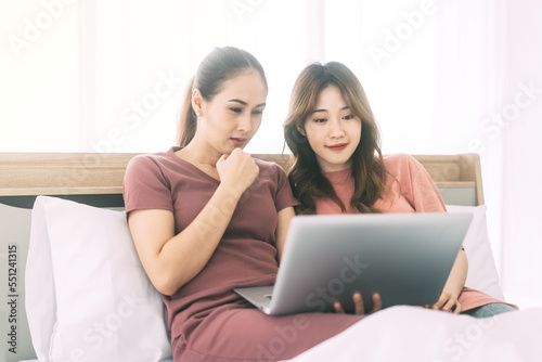 Two young adult woman living together with relationship laying at bedroom talking about work in the morning