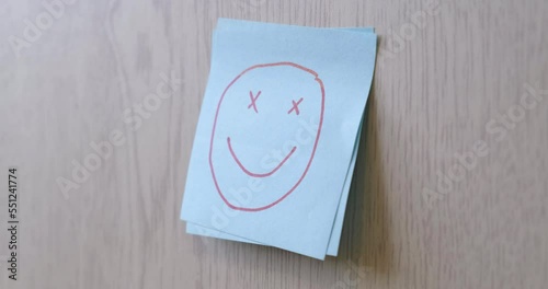 A man puts a sticker with a smiling funny face on a sticker with a sad face. The concept of motivation, success, despair, failure, victory, leadership, psychology