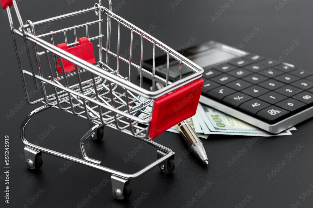 Shopping cart with calculator and money. Business concept.