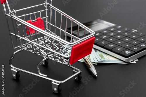 Shopping cart with calculator and money. Business concept.